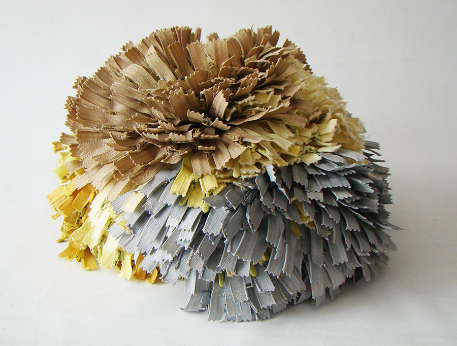 Cierres grises, amarillo claro y beiges amarrados en la base y que asemejan una flor de Hortensia